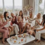 A group of women celebrating together in a stylish hotel suite, enjoying drinks and smiling.